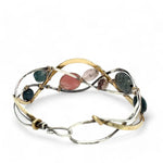 A oxidized sterling. brass, and sterling silver hammered wave bracelet featuring rhodochrosite, rose quartz, bloodstone, moss agate, and jasper gemstones on gold filled wire