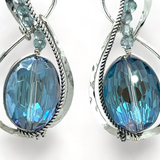 Pair of infinity shaped sterling silver earrings with blue crystal and apatite.