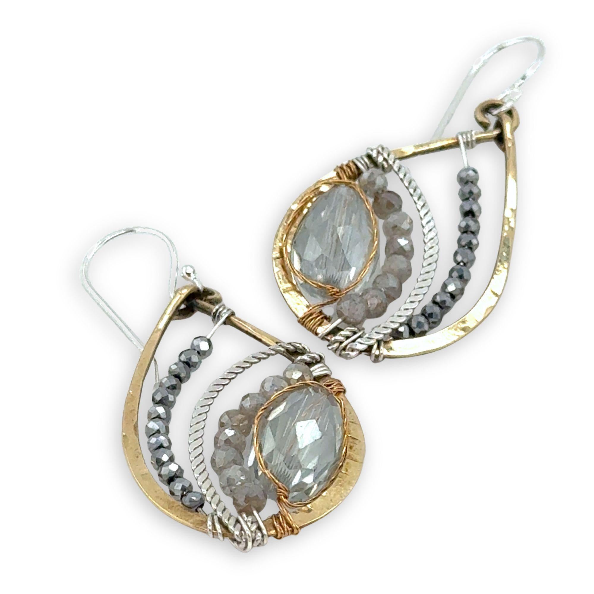 a light blue crystal drop wrapped in brass twist wire is surrounded by moonstone, pyrite gemstones, and hammered sterling silver hammered twist inside a mini brass teardrop earring