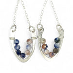 Horseshoe-shaped sterling silver earrings lined with sodalite blue and peach gemstones hanging on delicate silver chain