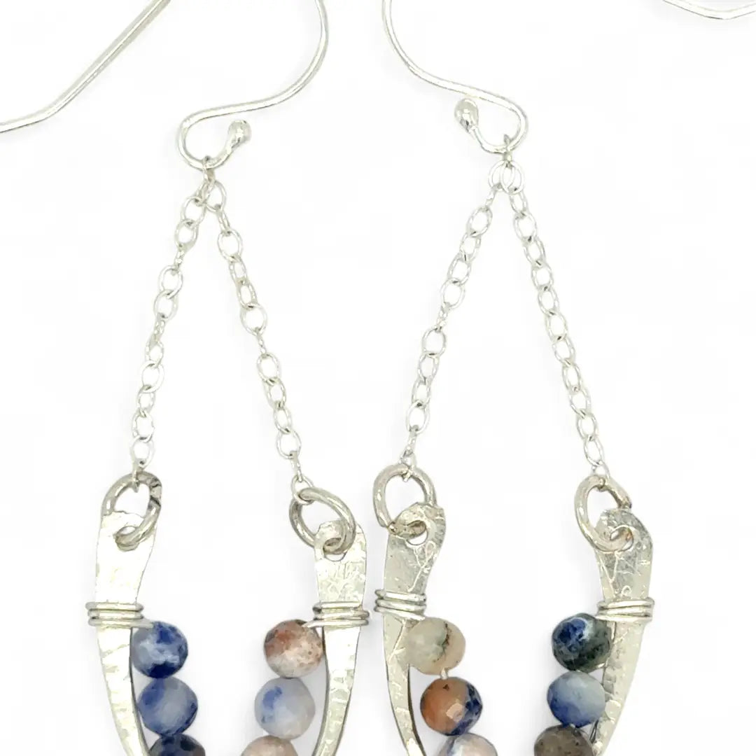 Horseshoe-shaped sterling silver earrings lined with sodalite blue and peach gemstones hanging on delicate silver chain