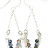 Horseshoe-shaped sterling silver earrings lined with sodalite blue and peach gemstones hanging on delicate silver chain