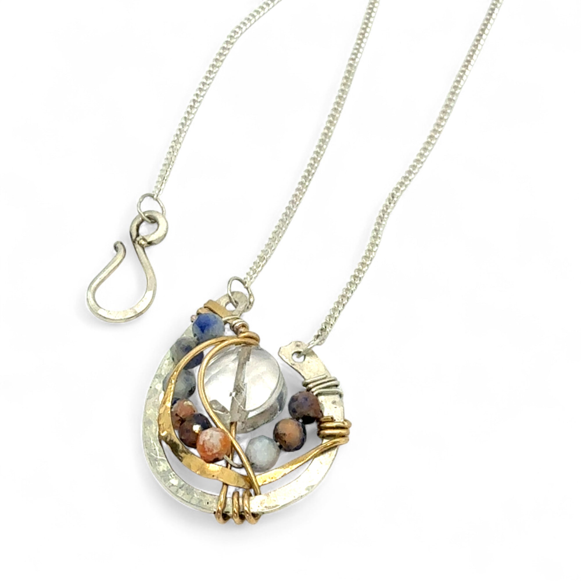 quartz coin surrounded by layers of hammered brass wire and sodalite gemstones within a mini sterling silver pendant necklace