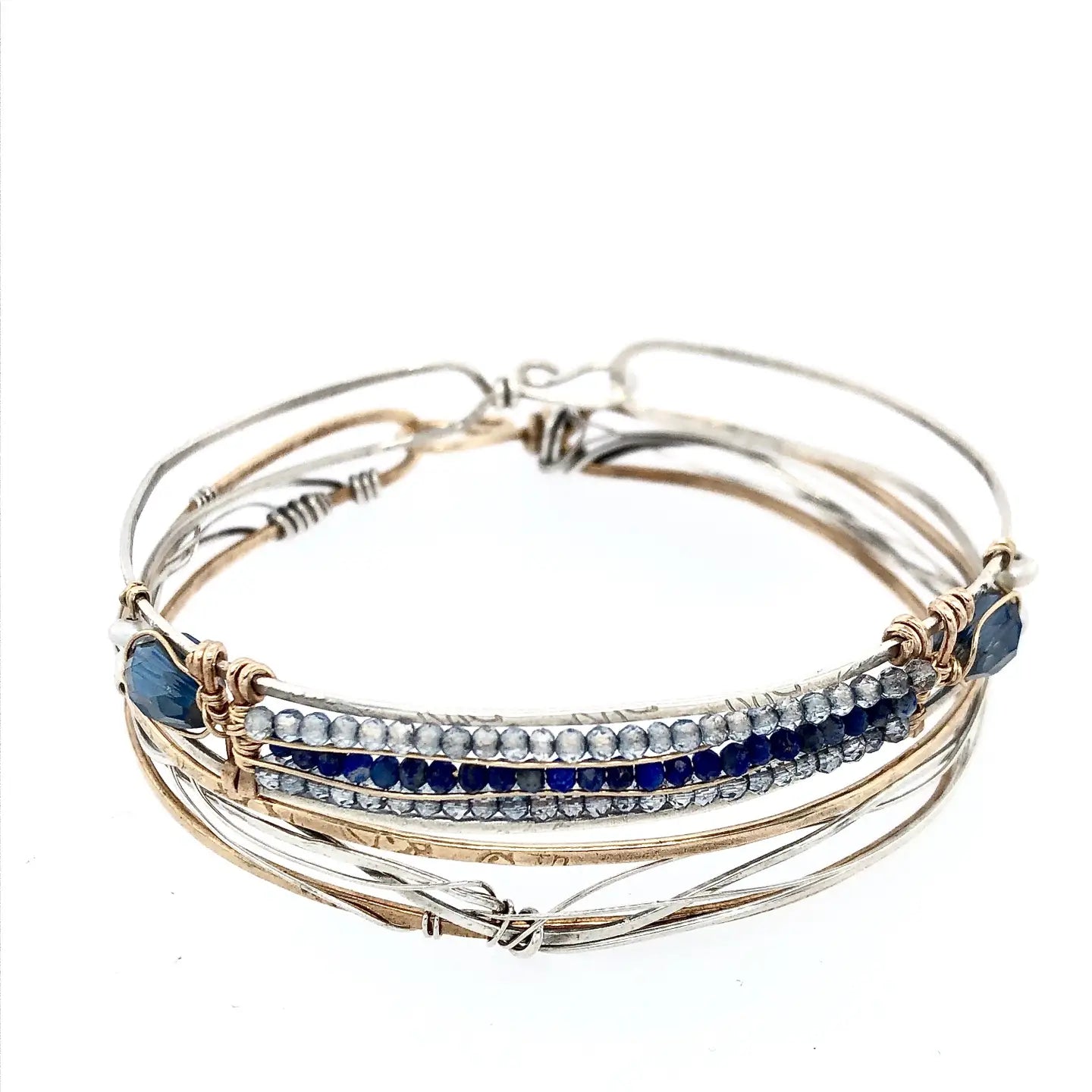 A slim handmade hammered sterling silver bracelet with bronze bars attached by lapis and blue quartz gemstones, on each side is accented with blue crystal drops and fresh water pearls
