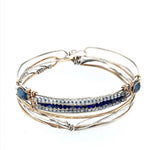 A slim handmade hammered sterling silver bracelet with bronze bars attached by lapis and blue quartz gemstones, on each side is accented with blue crystal drops and fresh water pearls