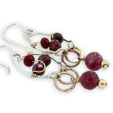 Sterling silver drop earrings with bronze rings holding a ruby faceted sphere, accented with garnet gemstones and red crystal