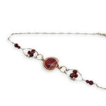 Red striped agate wrapped in hammered bronze wire suspended between sterling silver hammered petals holding faceted garnet and red crystal gemstones on a sterling silver bar chain necklace