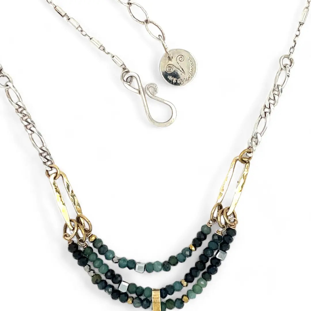 A necklace with blue tourmaline faceted ombre gemstones and silver crystal cubes, featuring a moss agate drop, hammered brass rectangle links, and a handmade hammered brass strap on sterling silver chain