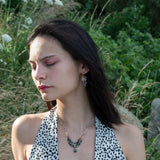 A necklace with blue tourmaline faceted ombre gemstones and silver crystal cubes, featuring a moss agate drop, hammered brass rectangle links, and a handmade hammered brass strap on sterling silver chain