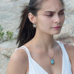 A sterling silver brass oval pendant necklace with a blue amazonite smooth gemstone drop and accents of micro faceted cats eye gems, atmospheric crystals, and gold-filled links on a delicate chain.