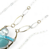 A sterling silver brass oval pendant necklace with a blue amazonite smooth gemstone drop and accents of micro faceted cats eye gems, atmospheric crystals, and gold-filled links on a delicate chain.