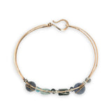 Flashy labradorite, aquamarine, iolite, and apatite gemstones wrapped tightly in sterling silver and brass twist wires are attached to a hammered bronze cuff bracelet