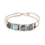 Flashy labradorite, aquamarine, iolite, and apatite gemstones wrapped tightly in sterling silver and brass twist wires are attached to a hammered bronze cuff bracelet