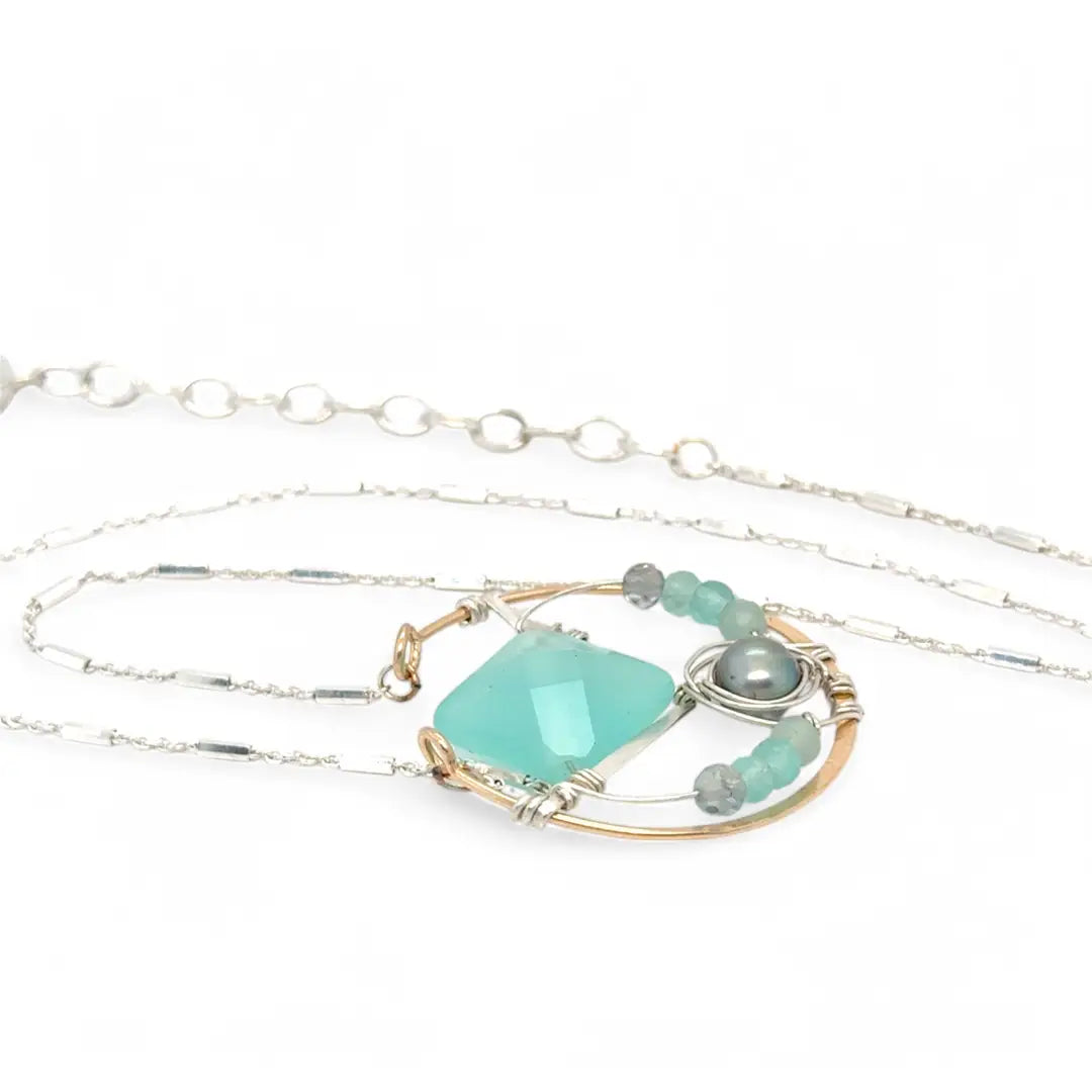 Bronze circle pendant necklace with hammered sterling silver inside holding a chalcedony mint colored diamond, accented with blue silver fresh water pearl and fluorite gemstones on delicate sterling silver chain