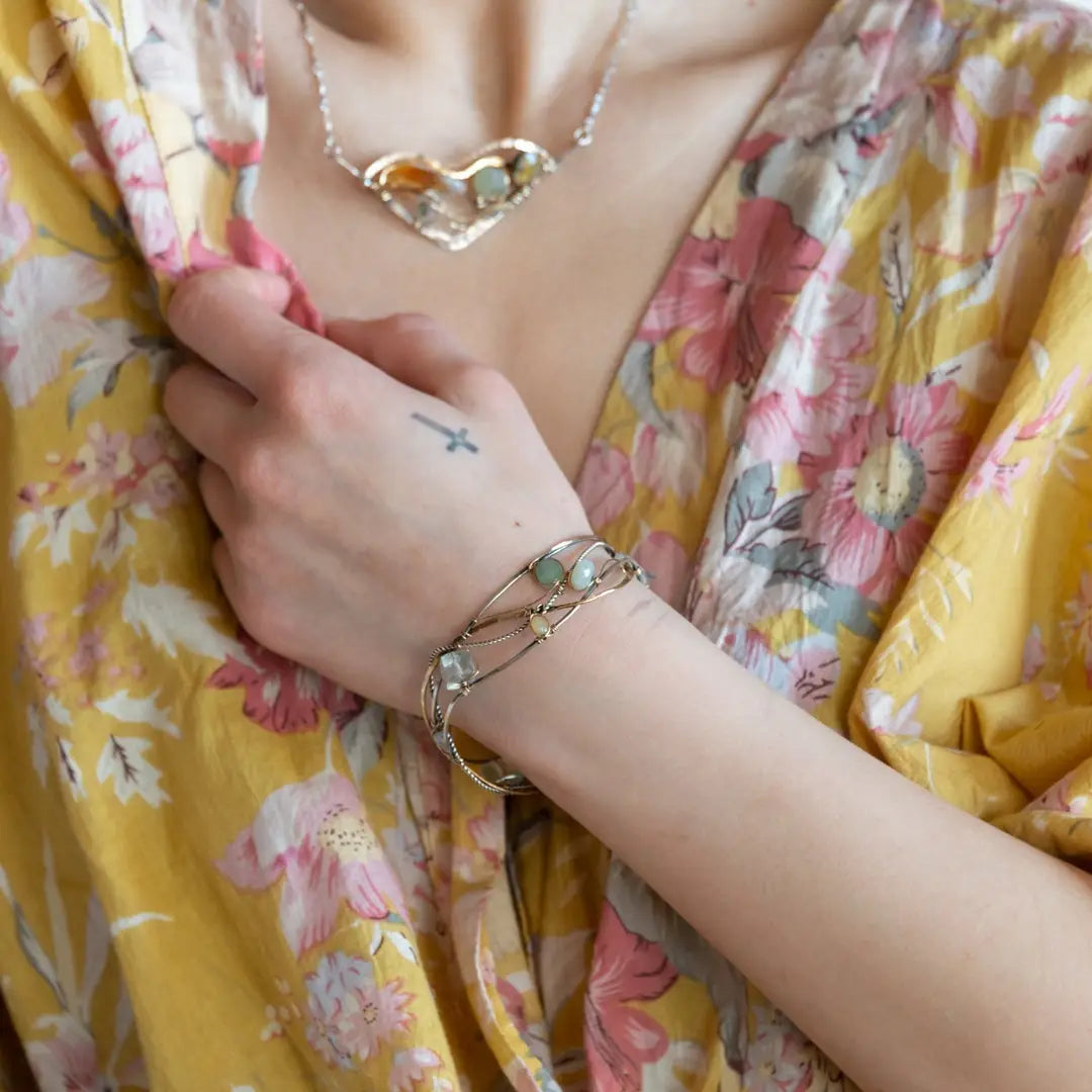 Oxidized sterling silver and brass hammered waves form a lovely cuff bracelet adorned with prehnite, jade, opal, and green amethyst gemstones on gold filled wire
