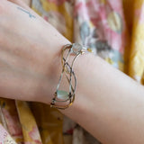 Oxidized sterling silver and brass hammered waves form a lovely cuff bracelet adorned with prehnite, jade, opal, and green amethyst gemstones on gold filled wire