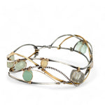 Oxidized sterling silver and brass hammered waves form a lovely cuff bracelet adorned with prehnite, jade, opal, and green amethyst gemstones on gold filled wire