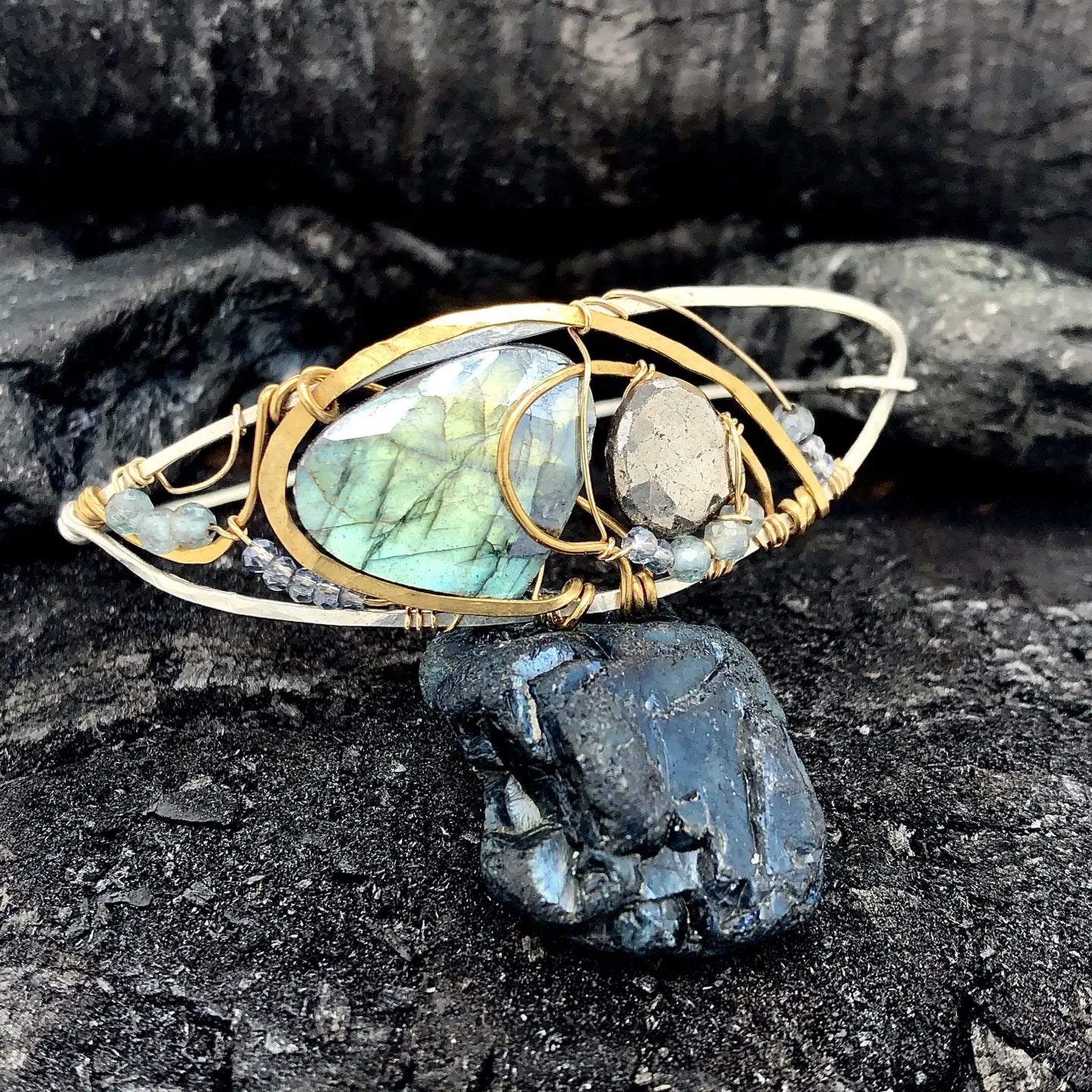 Flashy labradorite, pyrite, and apatite gemstones share space within a sterling silver and brass cuff bracelet with gold filled wire
