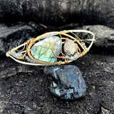 Flashy labradorite, pyrite, and apatite gemstones share space within a sterling silver and brass cuff bracelet with gold filled wire
