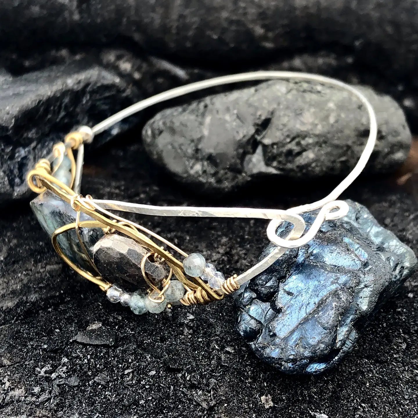 Flashy labradorite, pyrite, and apatite gemstones share space within a sterling silver and brass cuff bracelet with gold filled wire