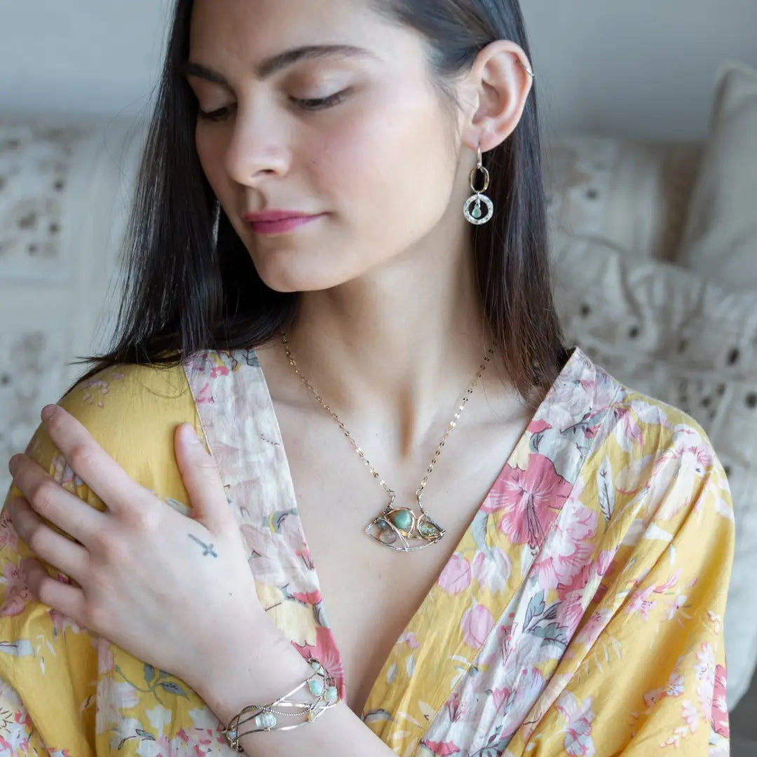 A dark sterling silver pendant necklace with gold-filled chain, featuring a turquoise drop, faceted green amethyst coin, and a golden sheen faceted moonstone in bronze wire