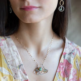 A dark sterling silver pendant necklace with gold-filled chain, featuring a turquoise drop, faceted green amethyst coin, and a golden sheen faceted moonstone in bronze wire