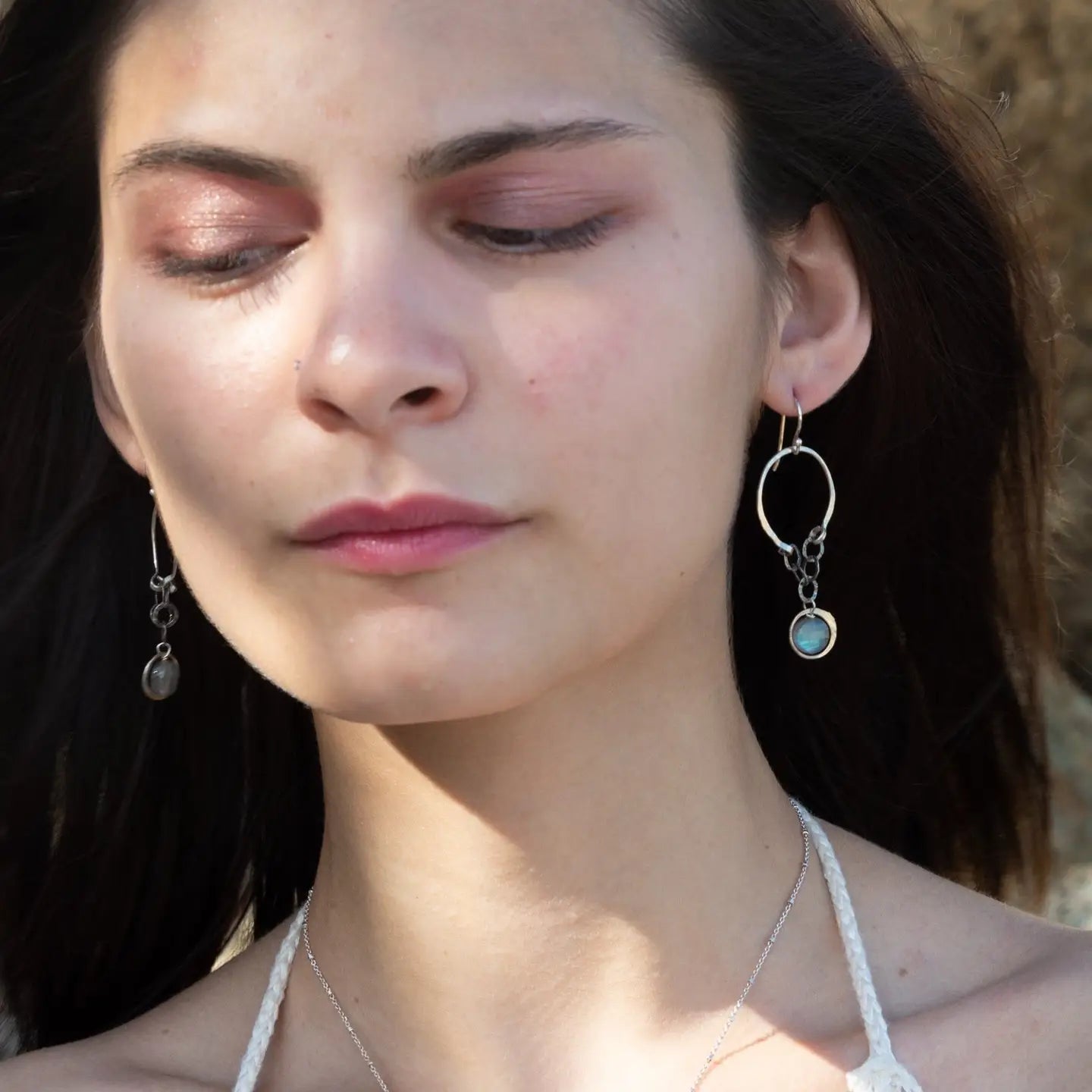 A pair of sterling silver hoop earrings with labradorite faceted coins inside mini sterling silver hammered rings, suspended from oxidized crinkle chain.
