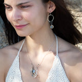 A pair of sterling silver hoop earrings with labradorite faceted coins inside mini sterling silver hammered rings, suspended from oxidized crinkle chain.