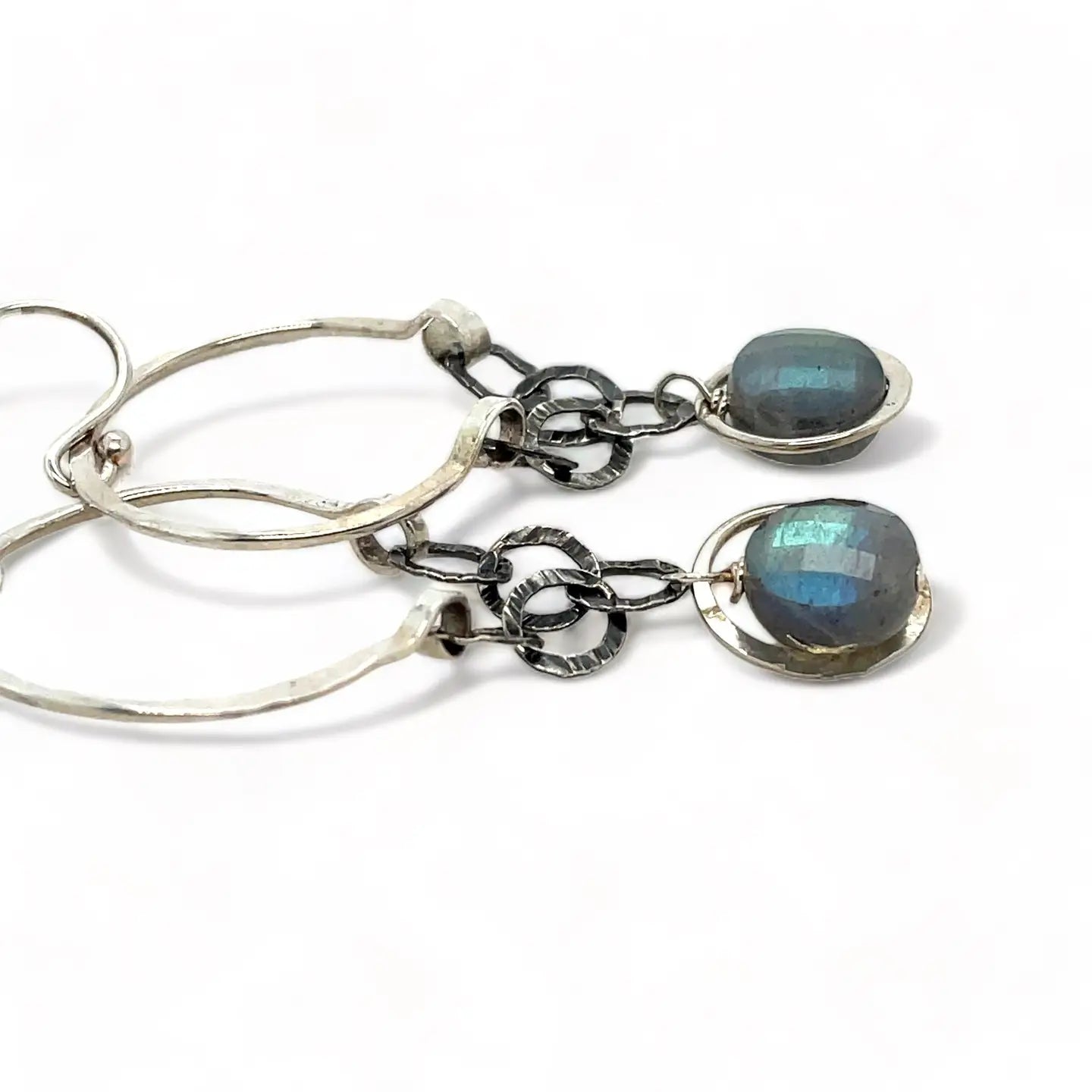 A pair of sterling silver hoop earrings with labradorite faceted coins inside mini sterling silver hammered rings, suspended from oxidized crinkle chain.