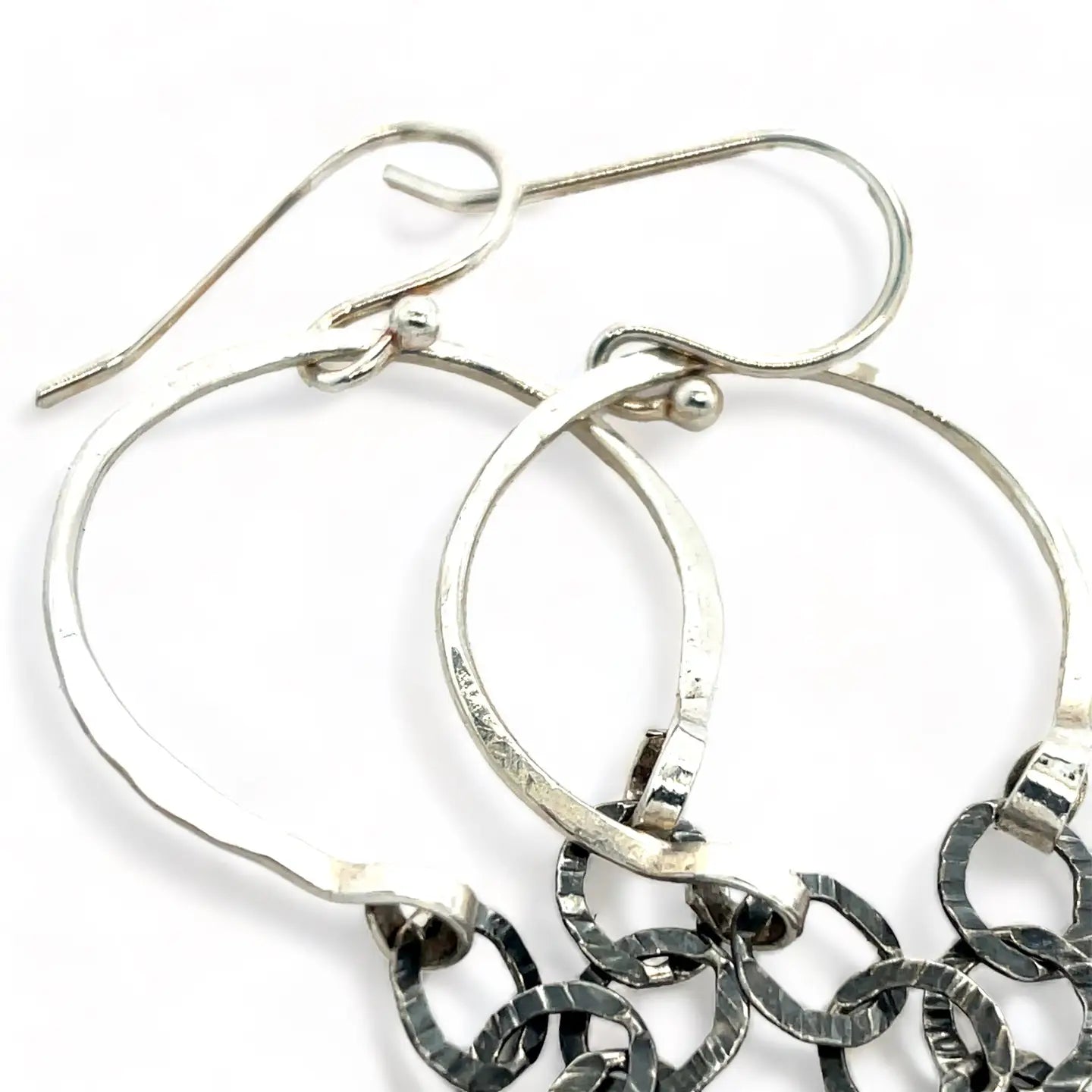A pair of sterling silver hoop earrings with labradorite faceted coins inside mini sterling silver hammered rings, suspended from oxidized crinkle chain.