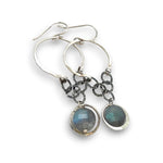 A pair of sterling silver hoop earrings with labradorite faceted coins inside mini sterling silver hammered rings, suspended from oxidized crinkle chain.