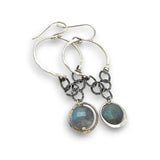 A pair of sterling silver hoop earrings with labradorite faceted coins inside mini sterling silver hammered rings, suspended from oxidized crinkle chain.