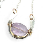 A sterling silver hammered necklace with gold-filled accents, featuring a faceted amethyst gemstone pendant and an adjustable chain with a handmade signature clasp.