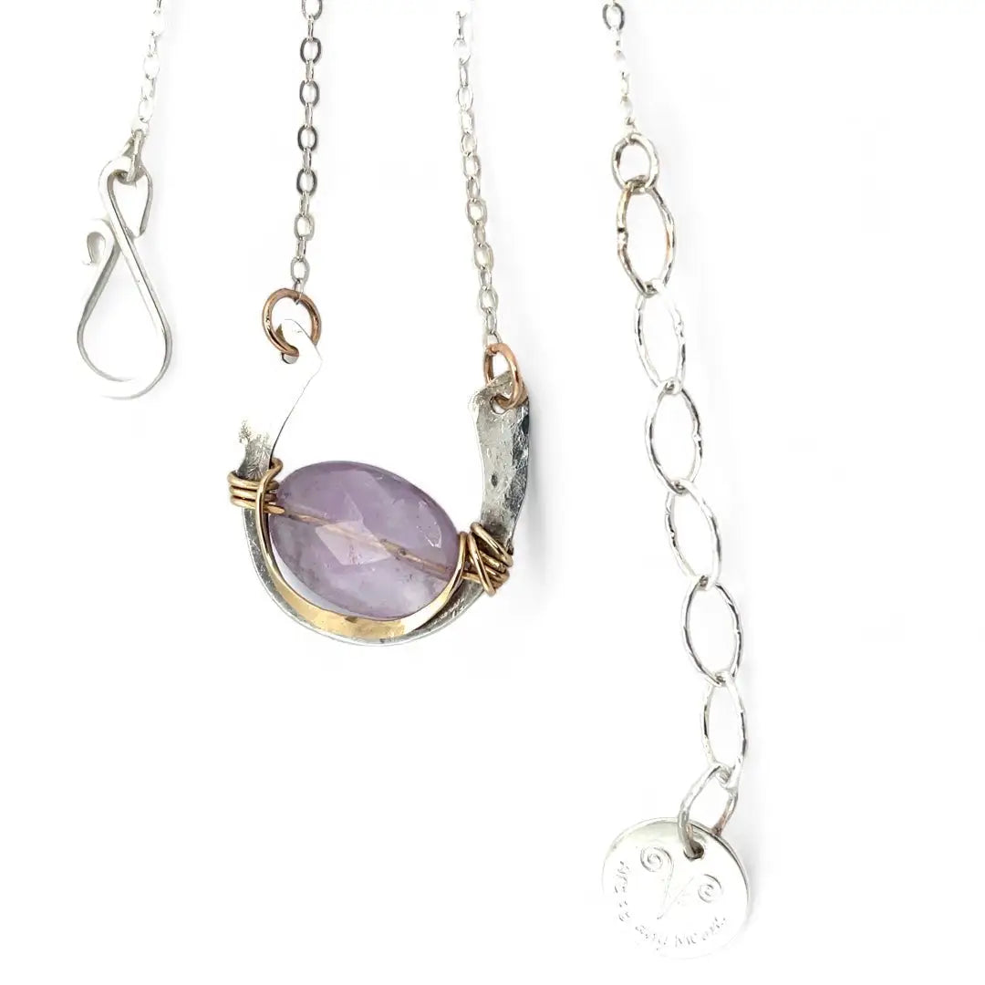 A sterling silver hammered necklace with gold-filled accents, featuring a faceted amethyst gemstone pendant and an adjustable chain with a handmade signature clasp.