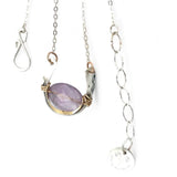A sterling silver hammered necklace with gold-filled accents, featuring a faceted amethyst gemstone pendant and an adjustable chain with a handmade signature clasp.