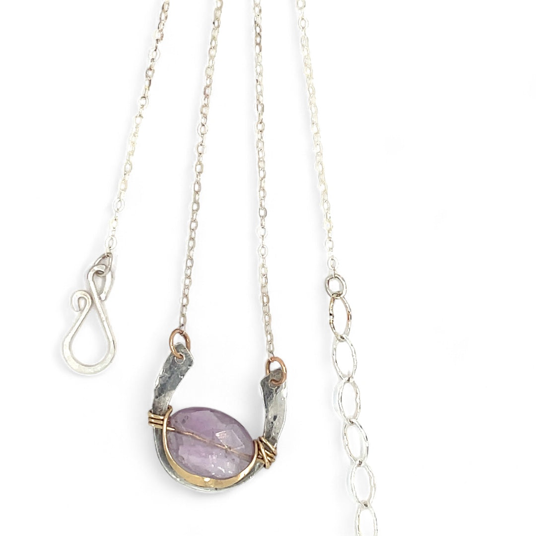 A sterling silver hammered necklace with gold-filled accents, featuring a faceted amethyst gemstone pendant and an adjustable chain with a handmade signature clasp.