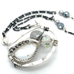 A sterling silver necklace with a pendant featuring fresh water pearl, moonstone, and pyrite gemstones, complemented by an oxidized sterling silver satellite chain.