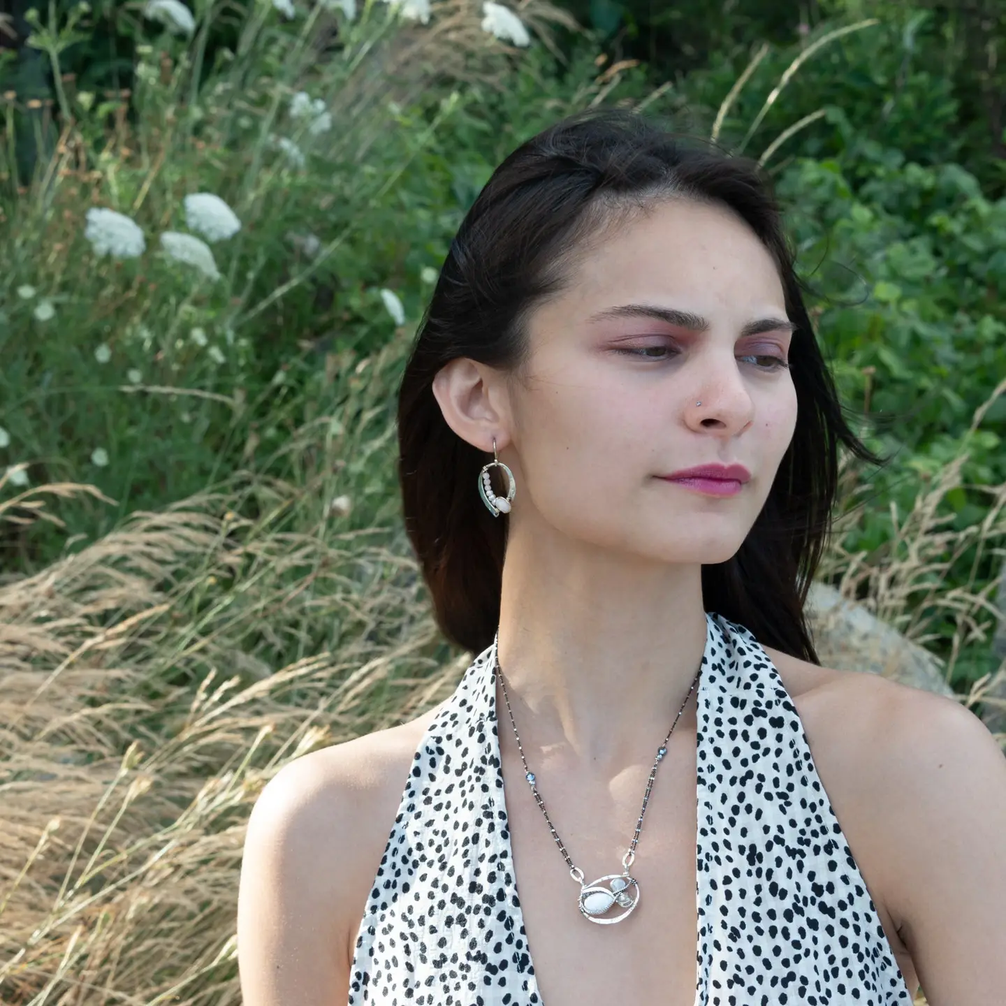 A sterling silver necklace with a pendant featuring fresh water pearl, moonstone, and pyrite gemstones, complemented by an oxidized sterling silver satellite chain.