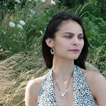 A sterling silver necklace with a pendant featuring fresh water pearl, moonstone, and pyrite gemstones, complemented by an oxidized sterling silver satellite chain.