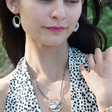 A sterling silver necklace with a pendant featuring fresh water pearl, moonstone, and pyrite gemstones, complemented by an oxidized sterling silver satellite chain.