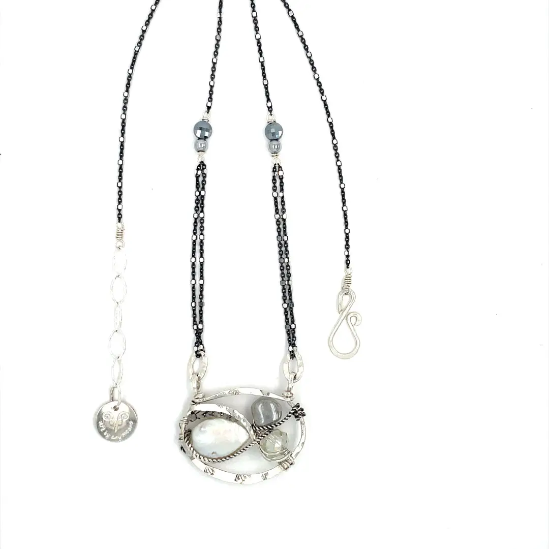 A sterling silver necklace with a pendant featuring fresh water pearl, moonstone, and pyrite gemstones, complemented by an oxidized sterling silver satellite chain.