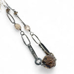 An adjustable sterling silver chain necklace with smokey quartz faceted gemstone nuggets and handmade sterling silver links with leaf patterns.