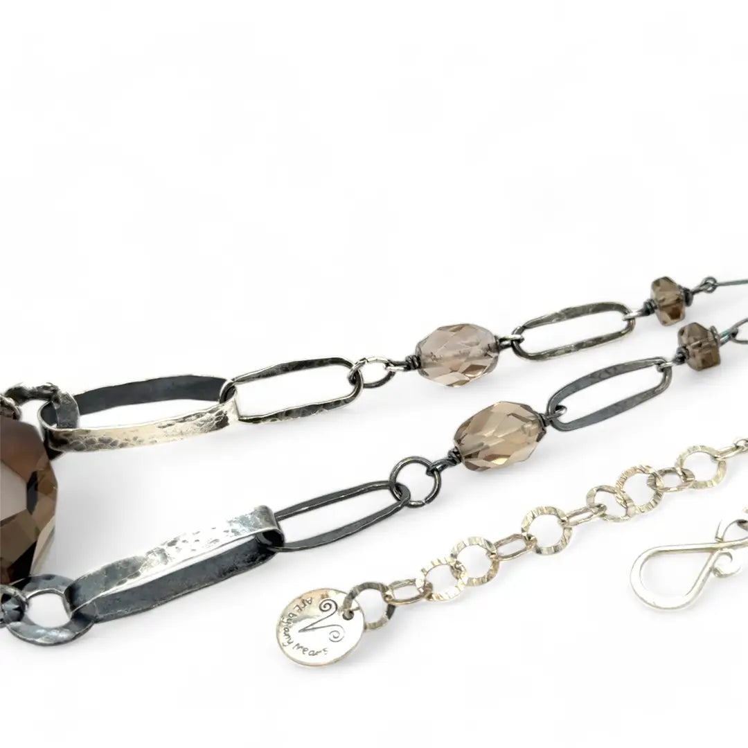 An adjustable sterling silver chain necklace with smokey quartz faceted gemstone nuggets and handmade sterling silver links with leaf patterns.