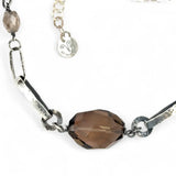 An adjustable sterling silver chain necklace with smokey quartz faceted gemstone nuggets and handmade sterling silver links with leaf patterns.