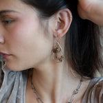 A pair of handcrafted sterling silver drop earrings with swirling bronze curls, featuring smokey quartz gemstones and freshwater pearls and pyrite