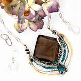 Handmade brass pendant necklace with smoky quartz faceted tile gemstone, embellished with smaller faceted pyrite, apatite, and chrysocolla, showcased with an oval silver chain and clasp