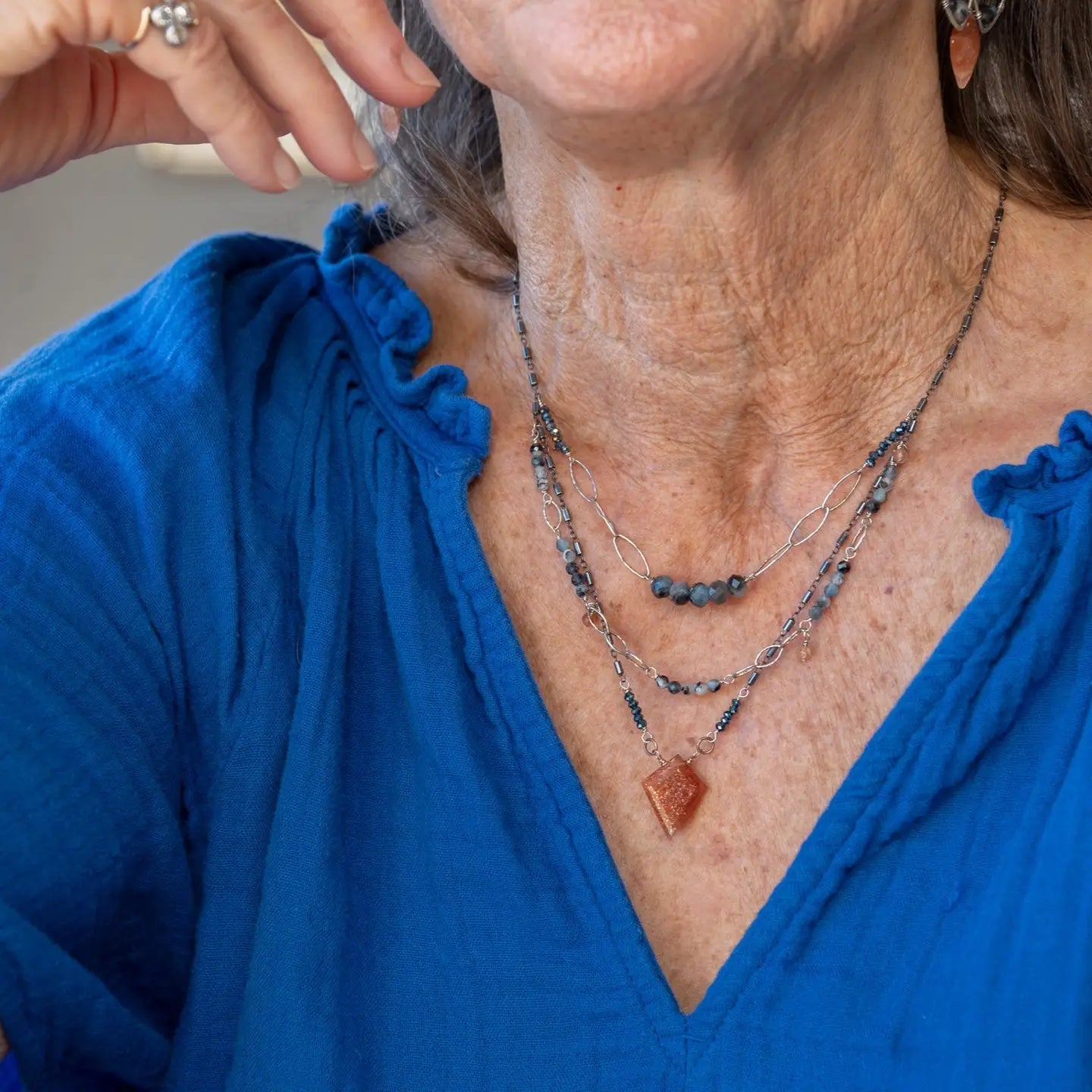 A triple strand chain style necklace with sunstone and aquamarine faceted gemstones, diamond cut sterling silver sparkly links, and oxidized sterling silver tube chain necklace