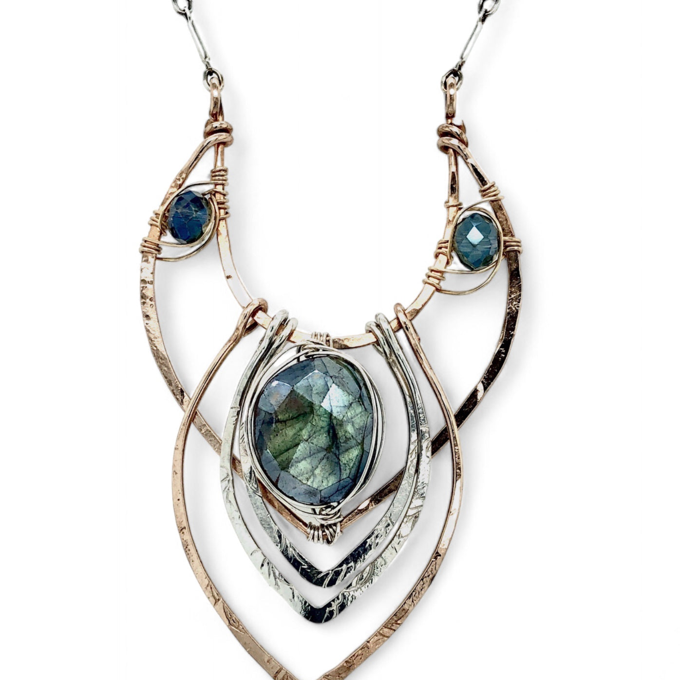 A leaf stamped silver and bronze necklace featuring a flashy labradorite gemstone with intricate metalwork and blue crystal accents on sterling silver bar chain