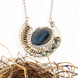 Faceted labradorite oval gemstones within a sterling silver pendant filled with pyrite gemstones and blue purple crystals and brass twist wire