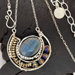 Faceted labradorite oval gemstones within a sterling silver pendant filled with pyrite gemstones and blue purple crystals and brass twist wire